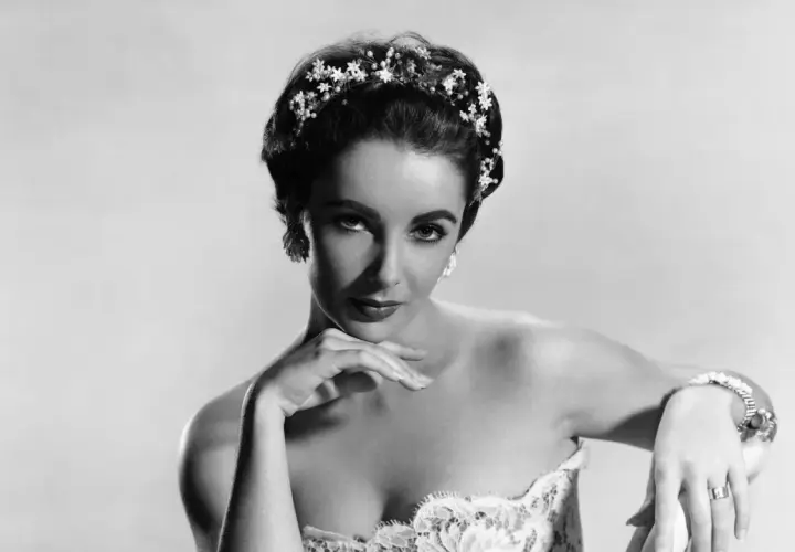 Elizabeth Taylor, con un tocado floral y un vestido de encaje, posa con elegancia.