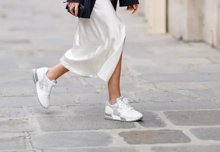 Elegante outfit: vestido blanco satinado con zapatillas deportivas blancas y plateadas.