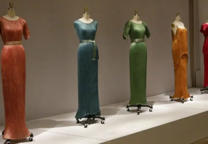 Cinco vestidos Delphos en tonos vibrantes: naranja, azul, verde, amarillo y rojo, exhibidos en maniquíes.