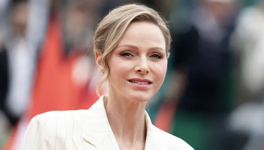 La princesa de Mónaco, Charlene Wittstock, sonríe con un traje blanco a rayas.