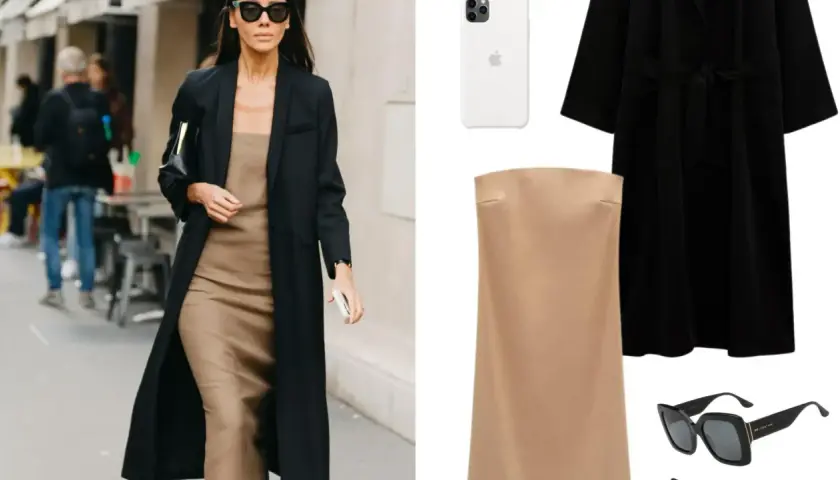 Mujer con estilo parisino, abrigo negro, vestido lencero beige, bolso negro y gafas de sol.
