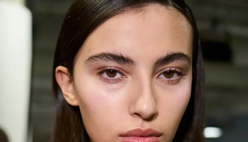 Primer plano de una joven con cejas pobladas y mirada intensa. Su piel luce natural y sus labios están ligeramente brillantes.