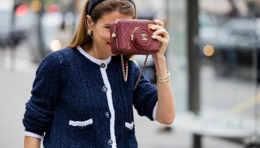 Mujer con chaqueta azul y bolso granate, demostrando cómo combinar granate y azul con estilo.