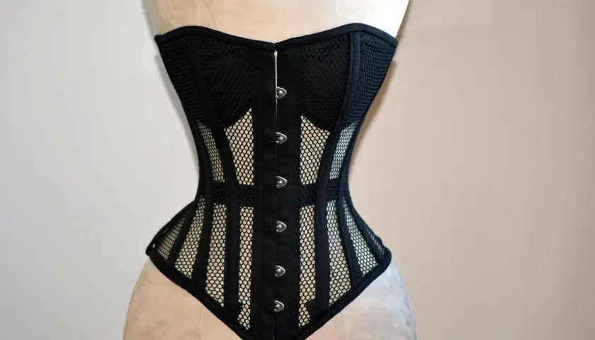 Corsé negro de malla con detalles de tela y broches plateados, diseñado para realzar la figura.