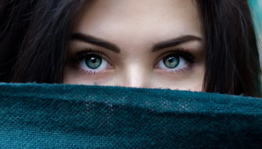 Ojos verdes penetrantes, enmarcados por cabello oscuro y un pañuelo. Un vistazo a la belleza que el microblading puede realzar.