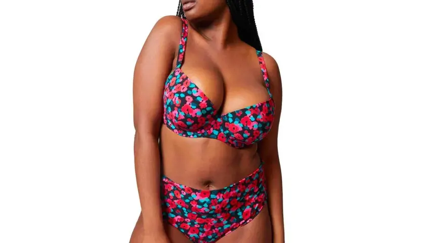 Mujer con bikini floral de tiro alto, ideal para realzar la figura y sentirse segura. ¿Qué bikini me favorece si tengo barriga? Este es un ejemplo.