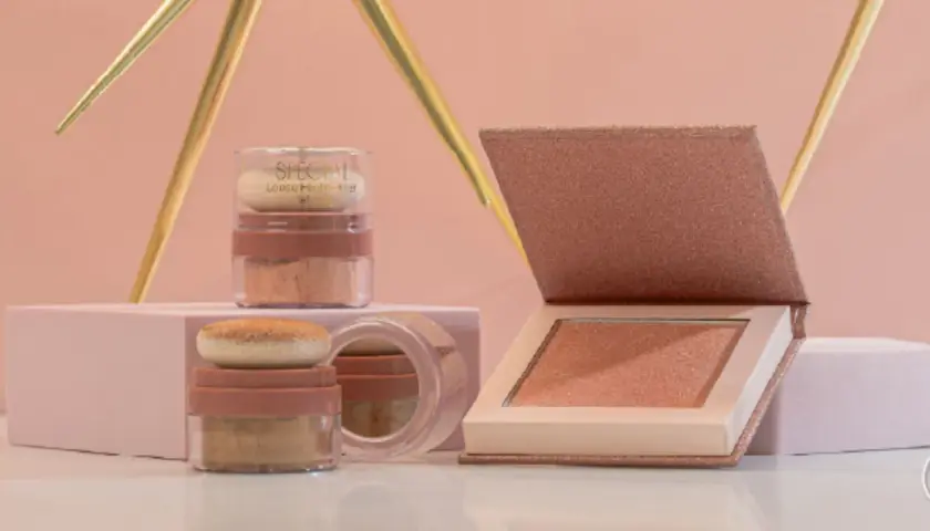 Dos envases de iluminador sueltos y un iluminador en polvo compacto, todos con tonos dorados y rosados, listos para dar luz a tu rostro.