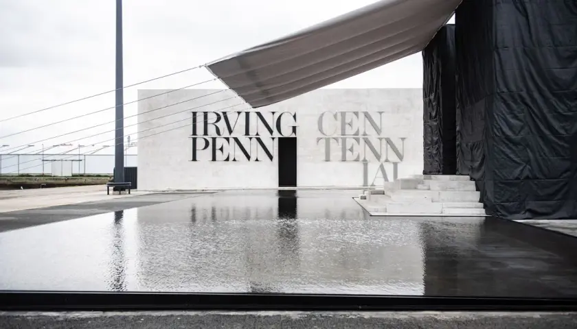 Reflejos en el agua de la entrada a la celebración del centenario de Irving Penn, con un toldo gris sobre la estructura.