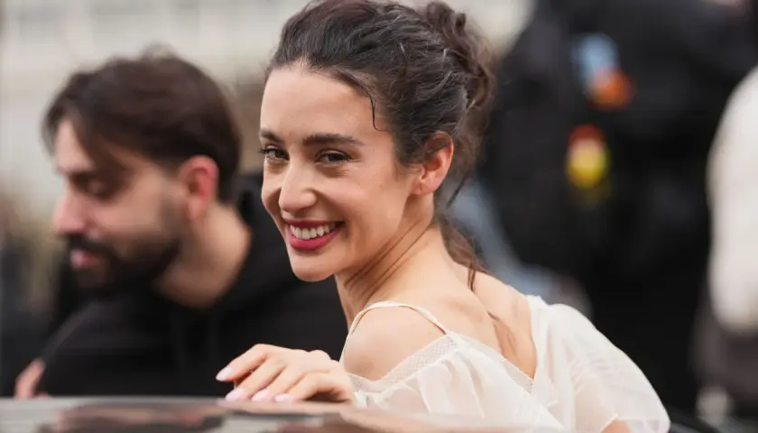 La belleza de Paula Badosa se refleja en su sonrisa radiante, con el cabello recogido y un vestido blanco delicado.