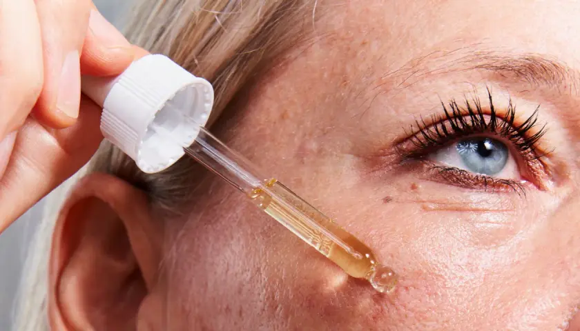 Una mano aplica un suero con un gotero sobre la piel. Descubre para qué sirve el retinol y cómo puede mejorar tu piel.