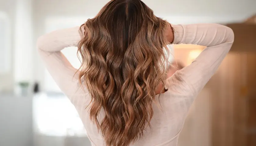 Melena castaña con ondas surferas, un estilo desenfadado y natural que realza la textura del cabello.
