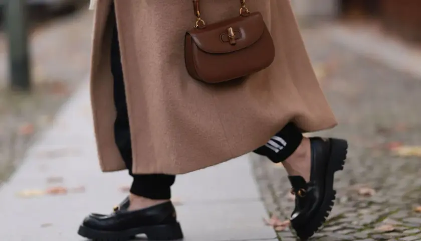 Abrigo camel, bolso marrón y mocasines negros. El marron y negro combinan a la perfección en este look otoñal.