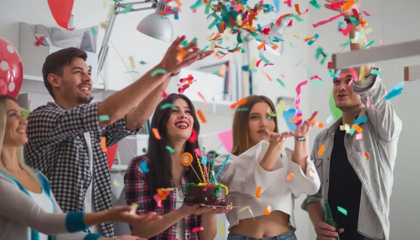 Jóvenes celebran un cumpleaños con confeti y pastel. ¡Una fiesta divertida para saber como vestir para un cumpleaños!