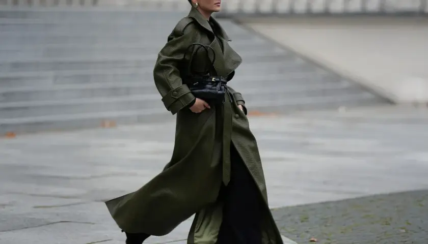 Mujer con abrigo verde olivo y bolso negro, demostrando colores que combinan con el negro.