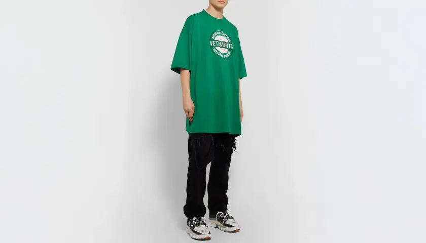 Camiseta verde de **oversize significado** con logo de Vetements, combinada con vaqueros negros rotos y zapatillas deportivas.