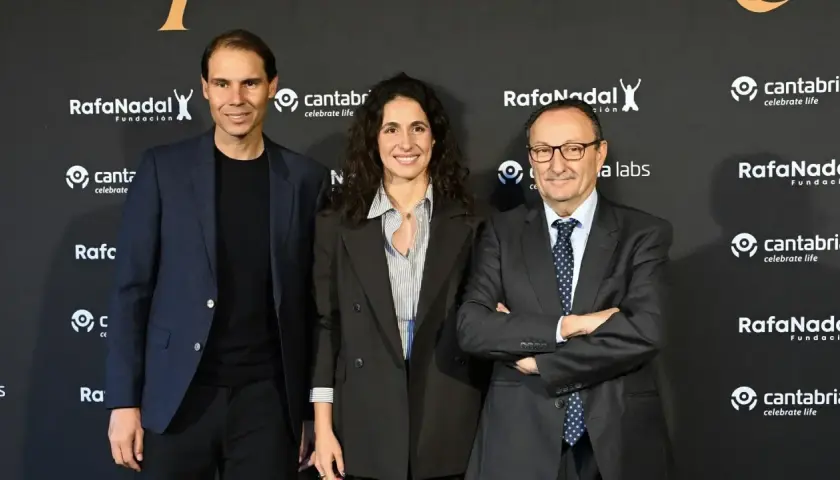 Rafael Nadal, Xisca Perelló y un hombre con traje posan ante un fondo con logos de la Fundación Rafa Nadal y Cantabria.