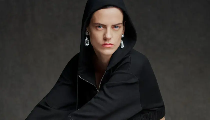 Modelo con sudadera negra con capucha y pendientes de lágrima, una visión audaz que evoca la estética de Pierpaolo Piccioli.