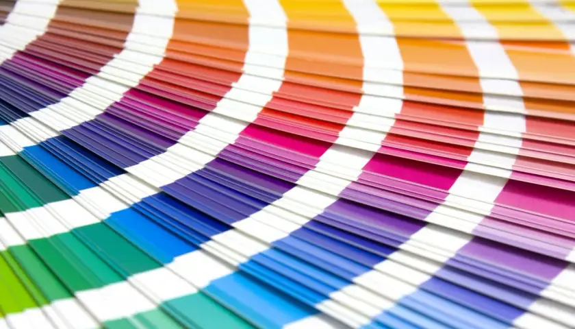 Abanico de muestras de color con tonos vibrantes, incluyendo el color burdeos y granate, que se despliegan en un arco iris de posibilidades.