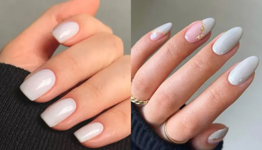 Manicura elegante con uñas blancas, algunas con detalles dorados y un toque de rosa pálido.