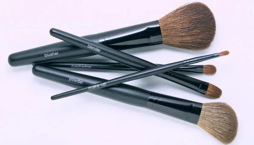 Un conjunto de brochas de maquillaje negras, etiquetadas como "blusher", "blender", "eyeshadow", "powder" y "make-up", listas para una limpieza profunda.