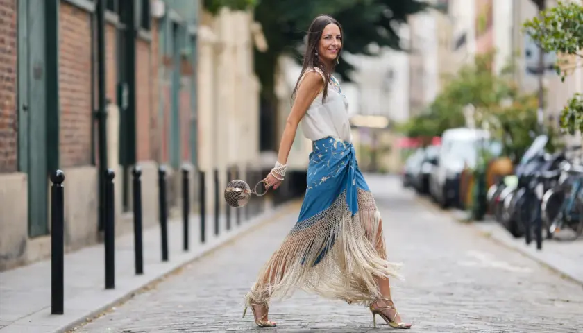 Mujer con falda larga azul con flecos y top blanco, perfecta ropa para ir a la feria de dia.