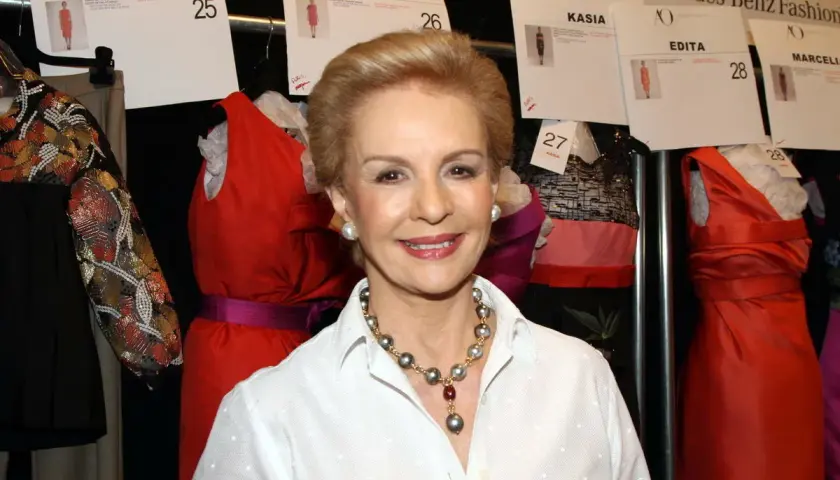 Carolina Herrera, icono de la moda, sonríe rodeada de vestidos de pasarela.