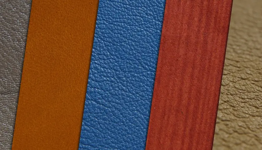 Muestras de materiales: cuero vegano azul, naranja y marrón, junto a un material rojo con vetas.