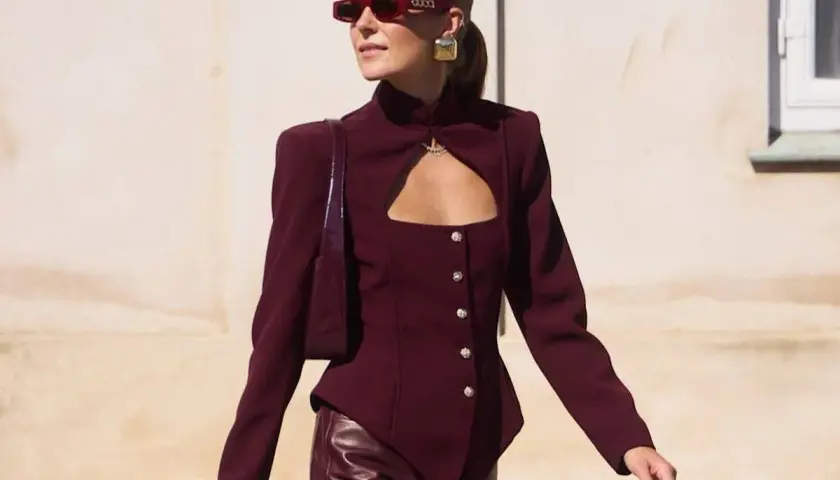 Mujer con gafas rojas y chaqueta granate con escote, combinando granate y rosa en su look audaz.