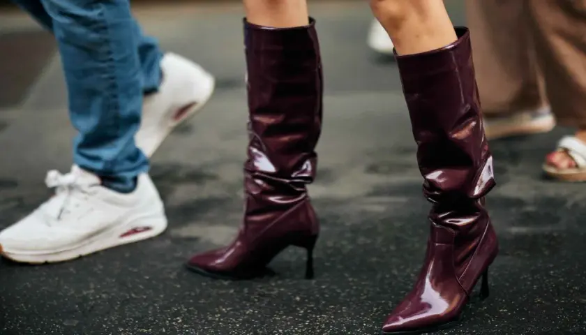 Se llevan las botas altas de charol burdeos, combinadas con vaqueros y zapatillas blancas.