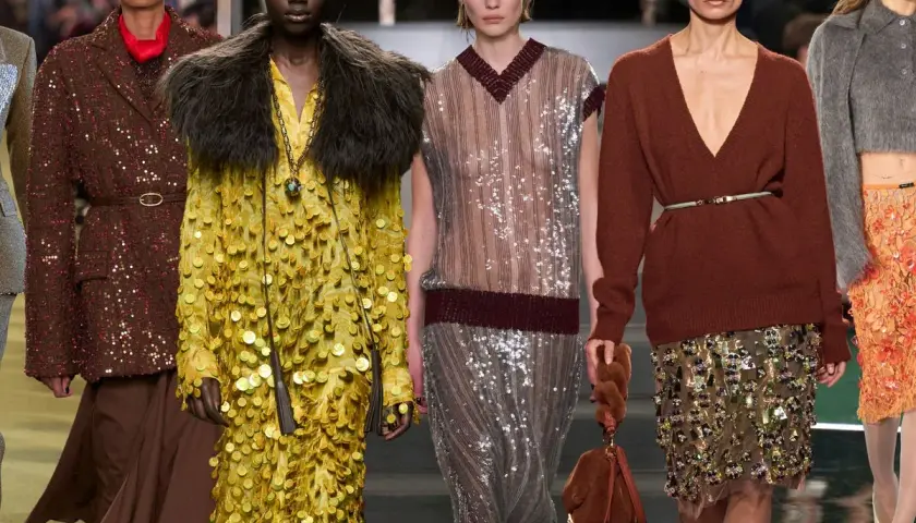 Modelos desfilan con atuendos brillantes. Un vestido amarillo con paillette y un traje marrón con lentejuelas destacan.