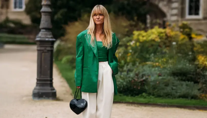 Mujer con traje verde brillante, top a juego y pantalones blancos. Muestra varios tipos de verde ropa en un look audaz.