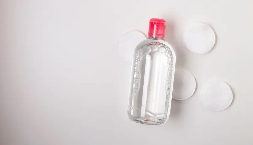 Botella de agua micelar con tapa rosa y discos de algodón. Ideal para limpiar ante y rostro.