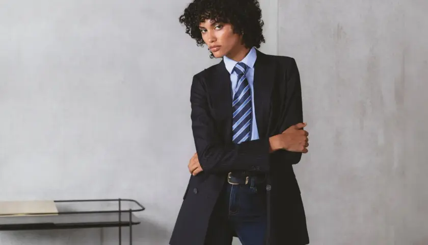 Persona andrógina con traje a rayas, camisa azul y corbata a juego.