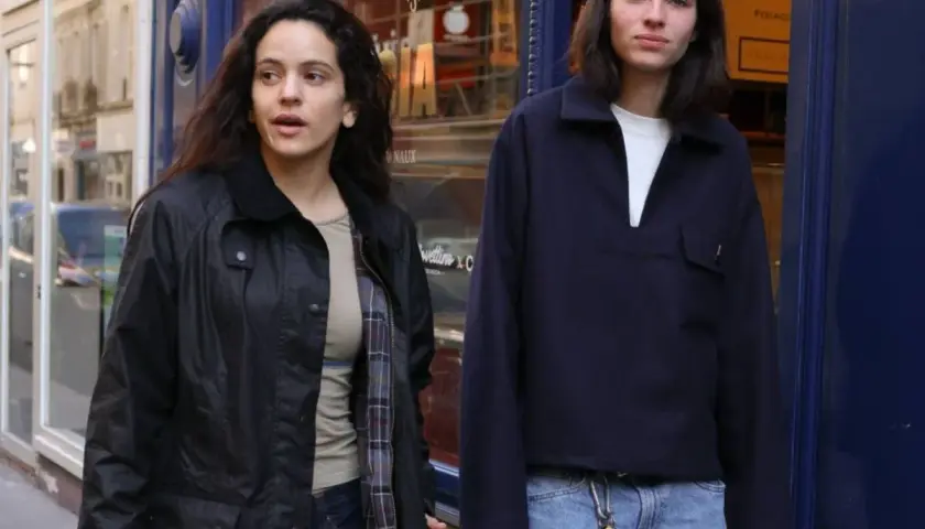 Dos jóvenes pasean por una calle, uno con chaqueta negra y el otro con jersey azul marino. Quizás buscando la loli bahía.