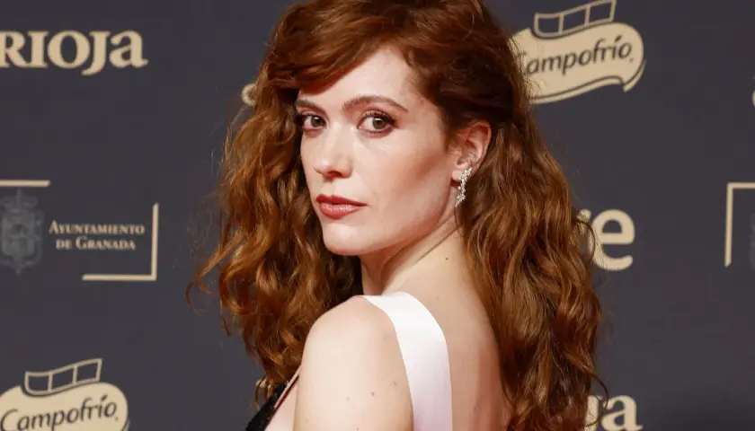Itsaso Arana, con su cabello pelirrojo ondulado y un vestido rosa, posa con elegancia.