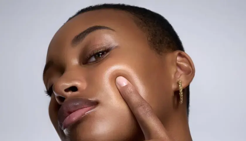 Piel oscura con un brillo dewy, resaltando sus pómulos y labios.