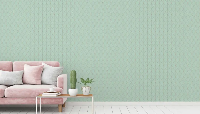 Sofá rosa y cojines blancos sobre suelo de madera. La pared de fondo tiene un patrón de rombos en colores que combinan con el verde agua.
