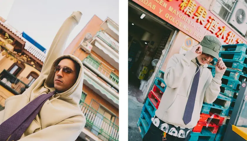 Ralphie Choo, con sudadera y corbata, posa con estilo urbano frente a un almacén.