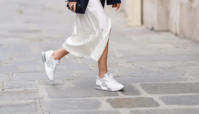 Elegante outfit: vestido blanco satinado con zapatillas deportivas blancas y plateadas.