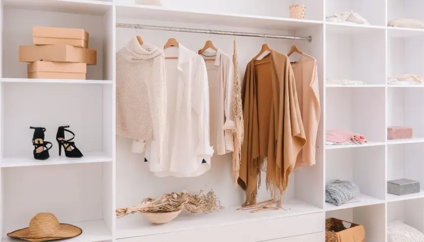 Armario organizado con ropa de punto, camisas y chales en tonos neutros, perfecto para tu colección de otoño.