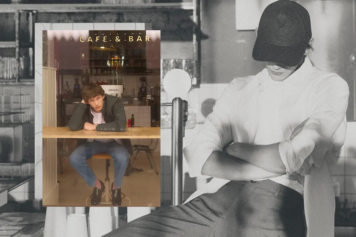 Un joven con un armario cápsula hombre, sentado en un café, reflexiona.