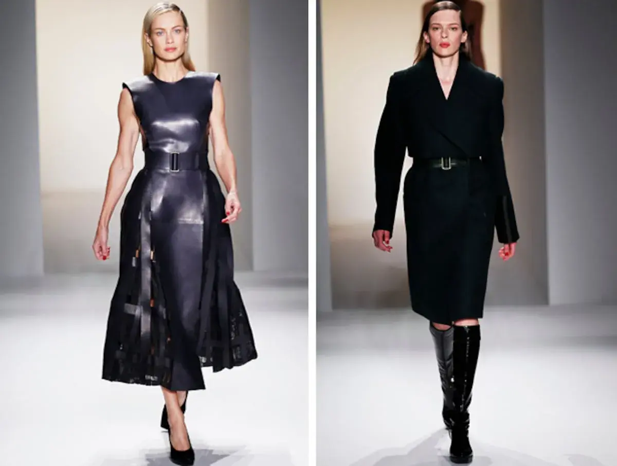 Modelos desfilan creaciones de Calvin Klein (diseñador): un vestido de cuero negro con falda plisada y un conjunto de abrigo y falda en tono oscuro con botas altas.