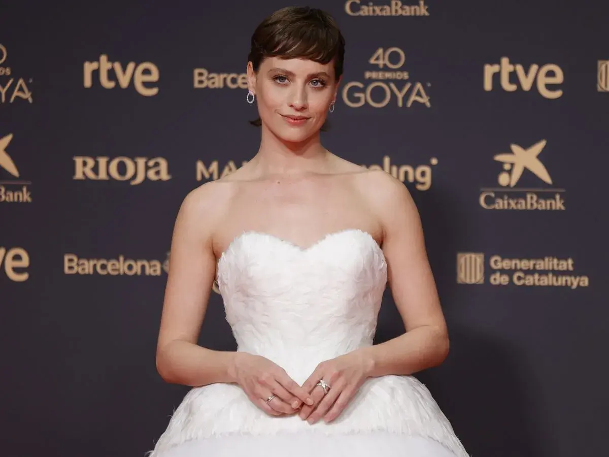 Una actriz posa en la goya alfombra roja con un vestido blanco voluminoso.