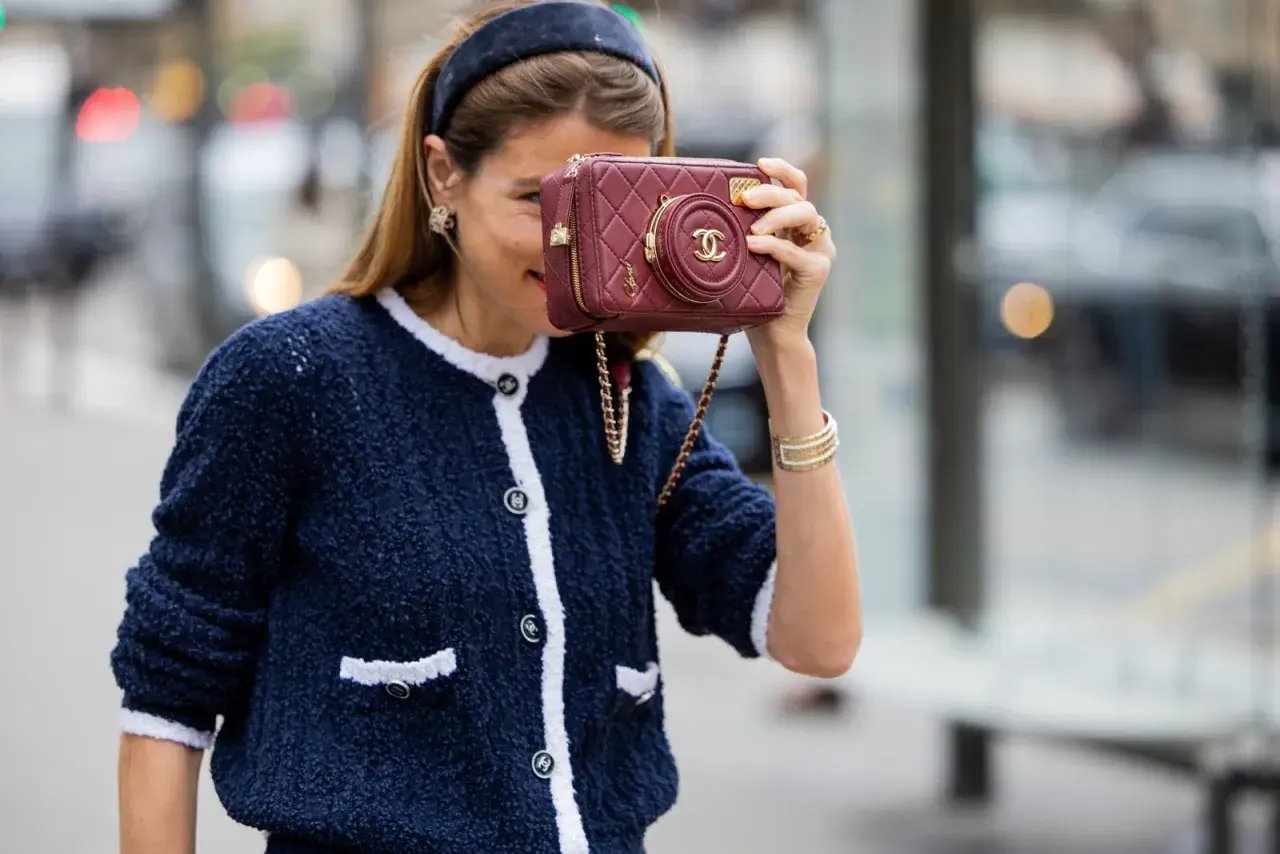 Mujer con chaqueta azul y bolso granate, demostrando cómo combinar granate y azul con estilo.
