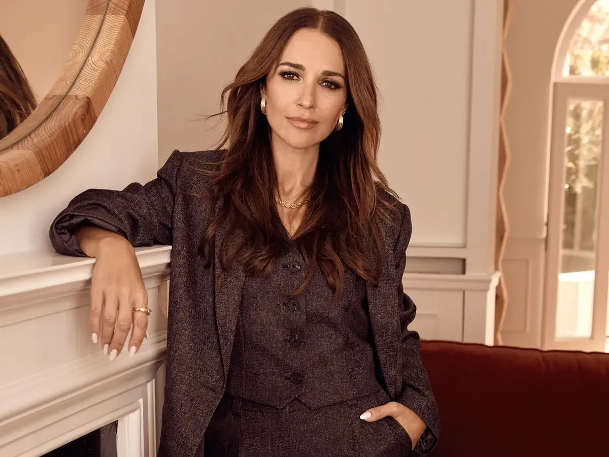 Paula Echevarría luce elegante con traje de Primark, apoyada en una chimenea.