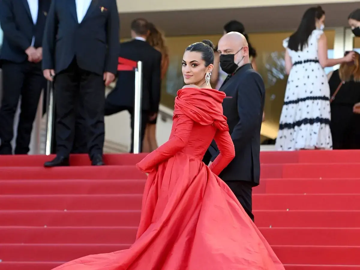 Una mujer luce un espectacular vestido rojo en la alfombra, demostrando cómo combinar un vestido rojo con elegancia y glamour.