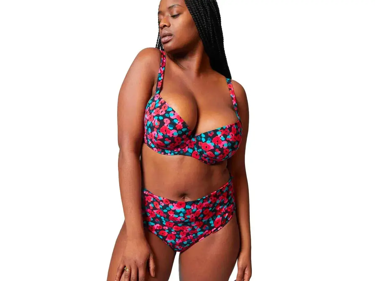Mujer con bikini floral de tiro alto, ideal para realzar la figura y sentirse segura. ¿Qué bikini me favorece si tengo barriga? Este es un ejemplo.