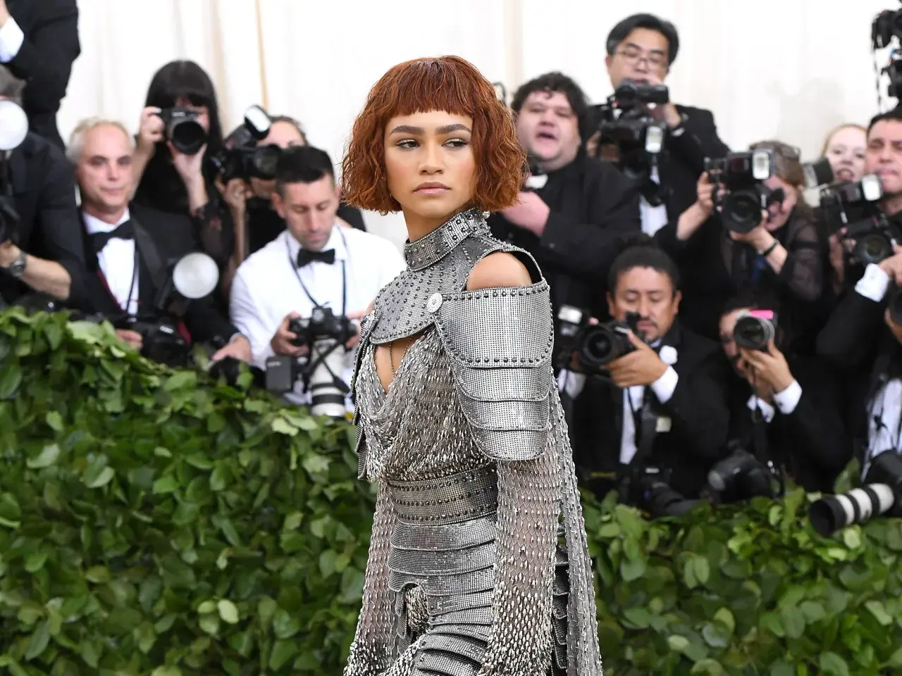 Zendaya, deslumbrante con armadura plateada, posa ante la prensa en un evento.
