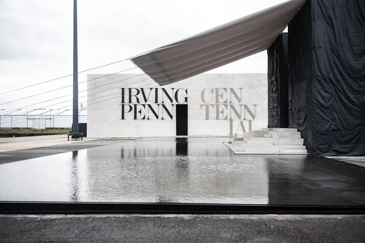 Reflejos en el agua de la entrada a la celebración del centenario de Irving Penn, con un toldo gris sobre la estructura.