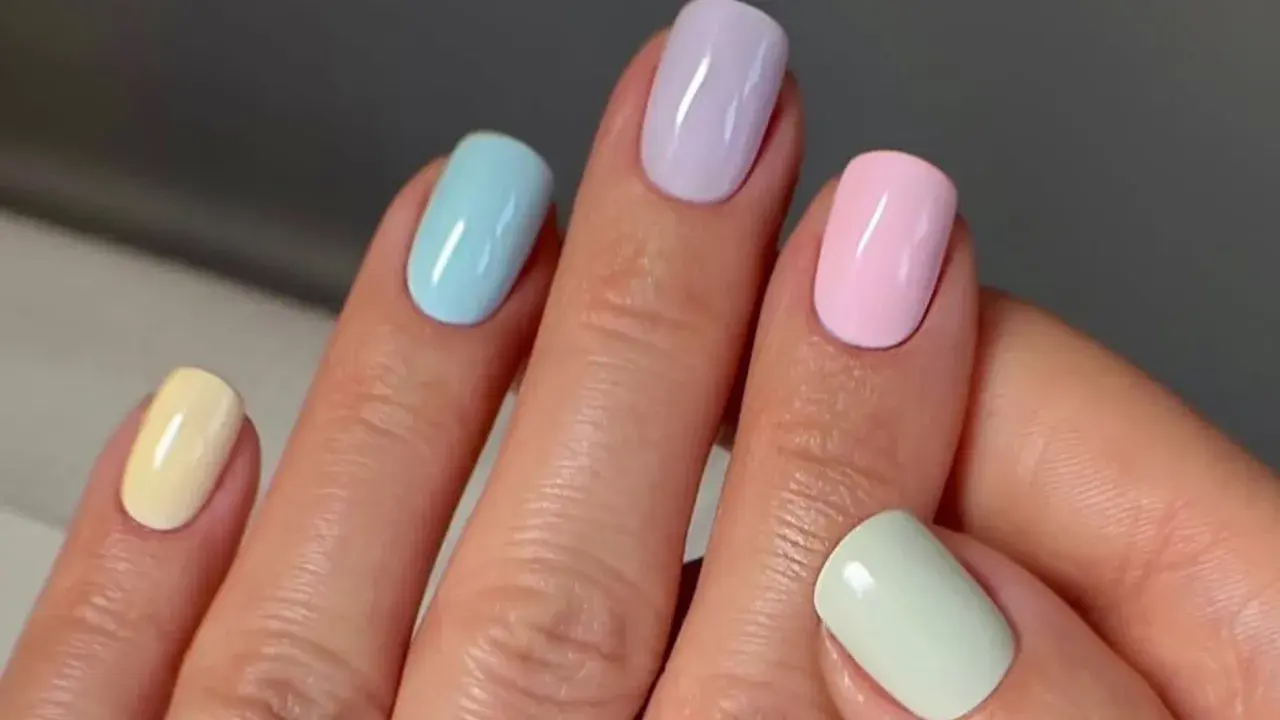 Manos con uñas de verano elegantes en tonos pastel: amarillo, azul, lila, rosa y verde menta.